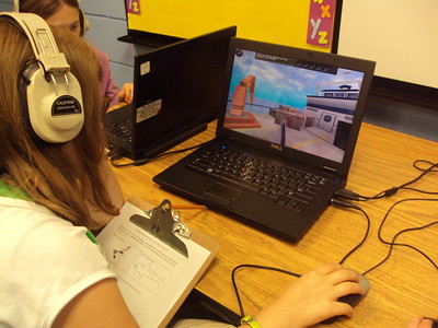 A person sitting at a desk with a computer
Description automatically generated